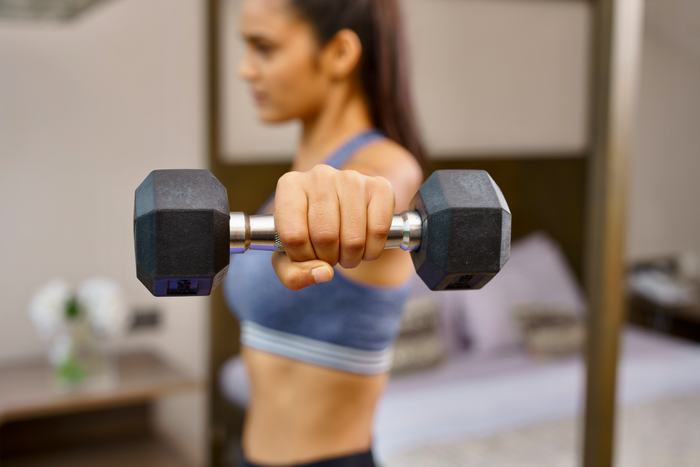 Woman pressing a Cube Club hex dumbbell at home